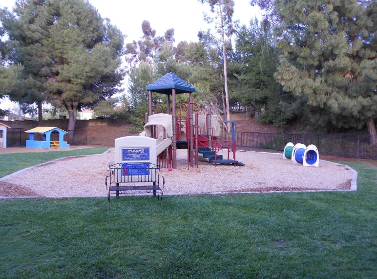 Playground with slides, tunnels, and a small playhouse on a sandy area