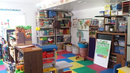 Playroom with colorful floor mats and shelves filled with toys and books