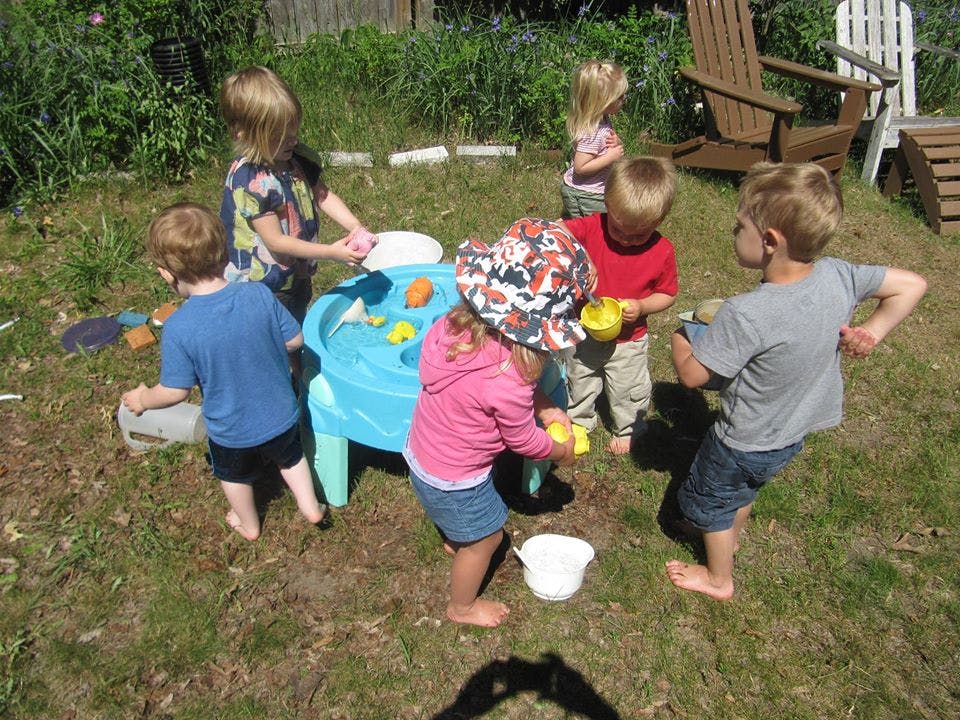 Children playing around a water table outdoors
