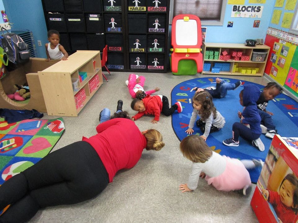 Adult and children crawling on the floor in a classroom