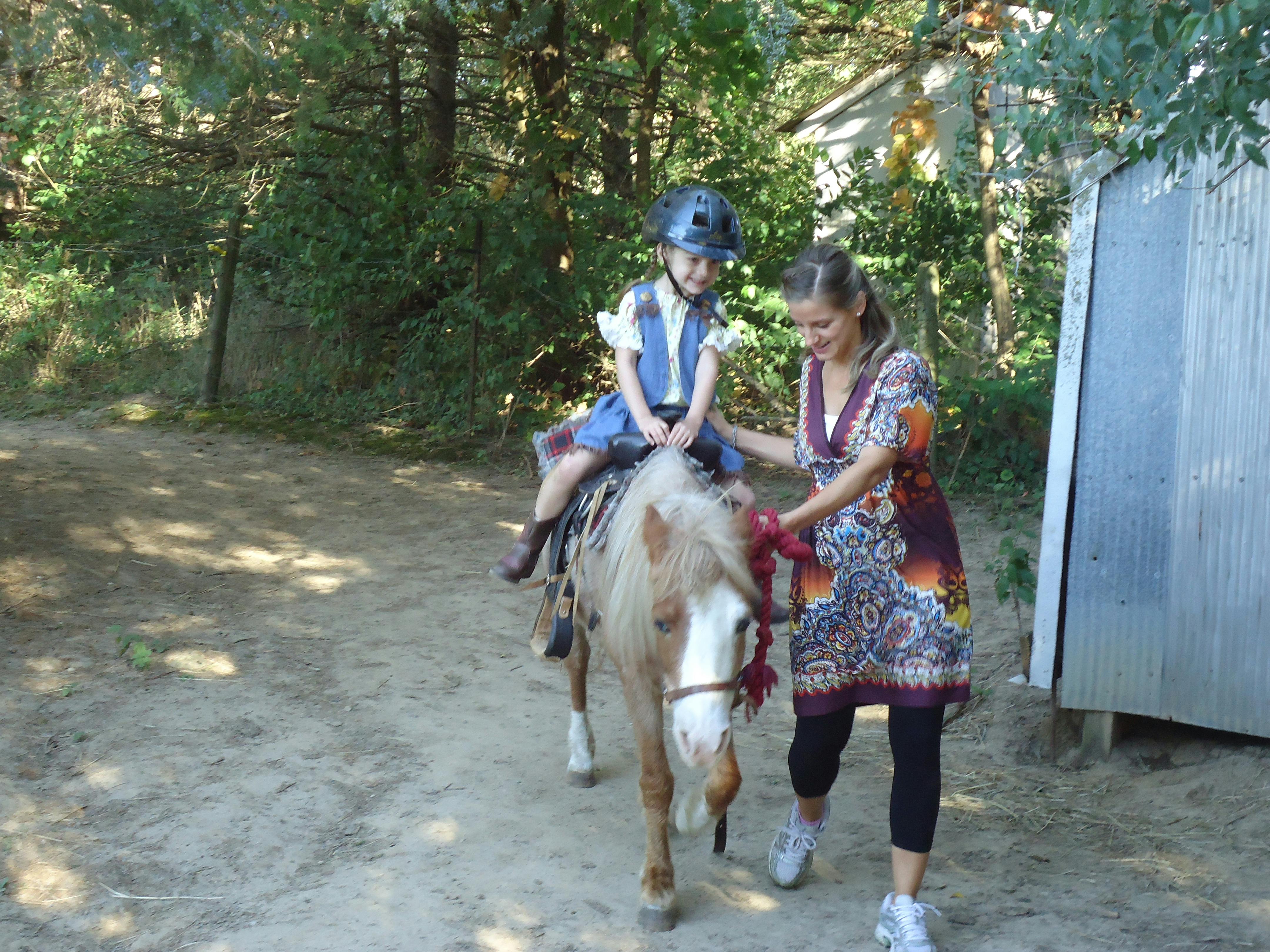 Person leading a child on a pony
