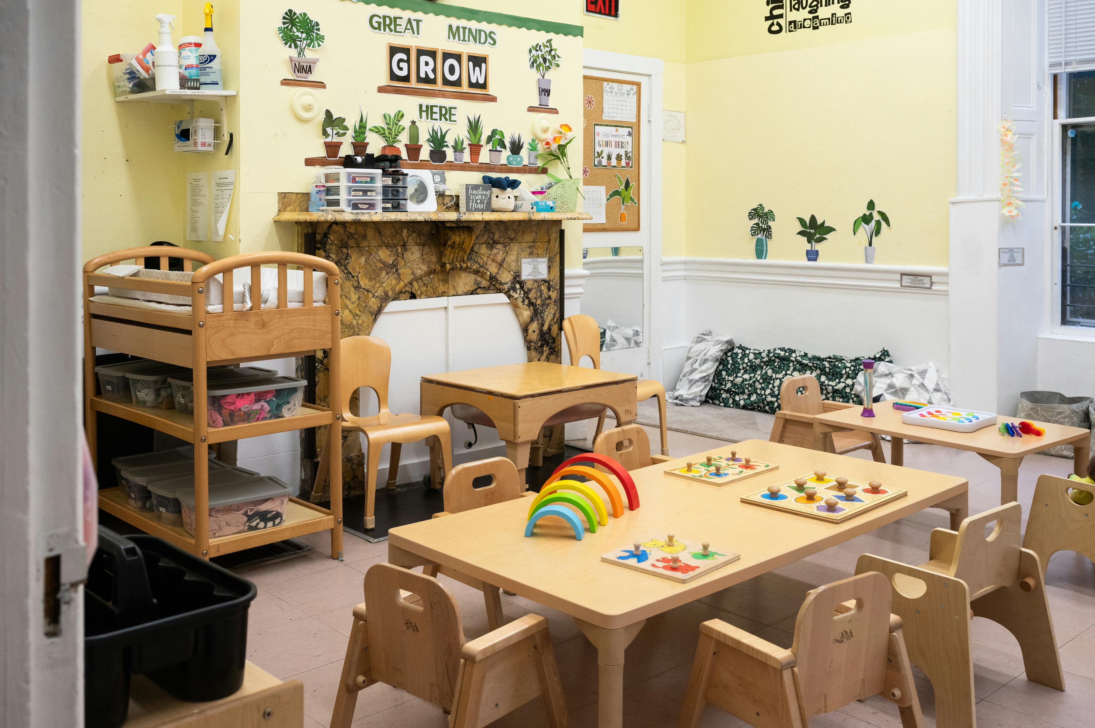 Childcare classroom with small wooden tables, chairs, and learning toys