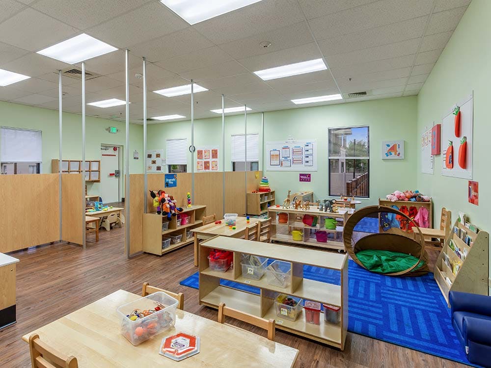 Empty early childhood classroom with cubbies, tables, and a reading nook