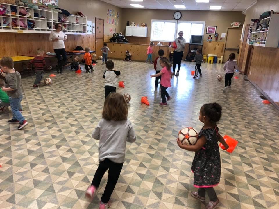 Children playing with balls and orange cones in a large room