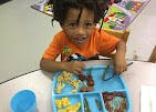 Child playing with toy animals at a table