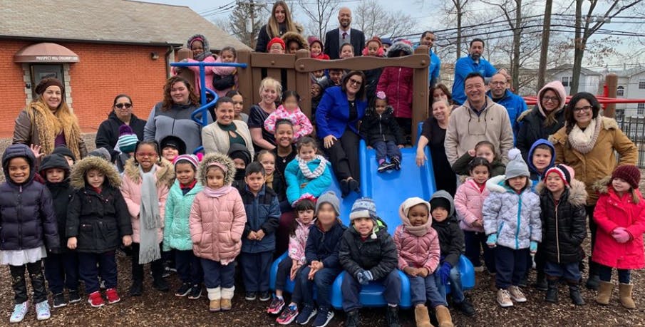 Group of adults and children posing on and around a playground structure