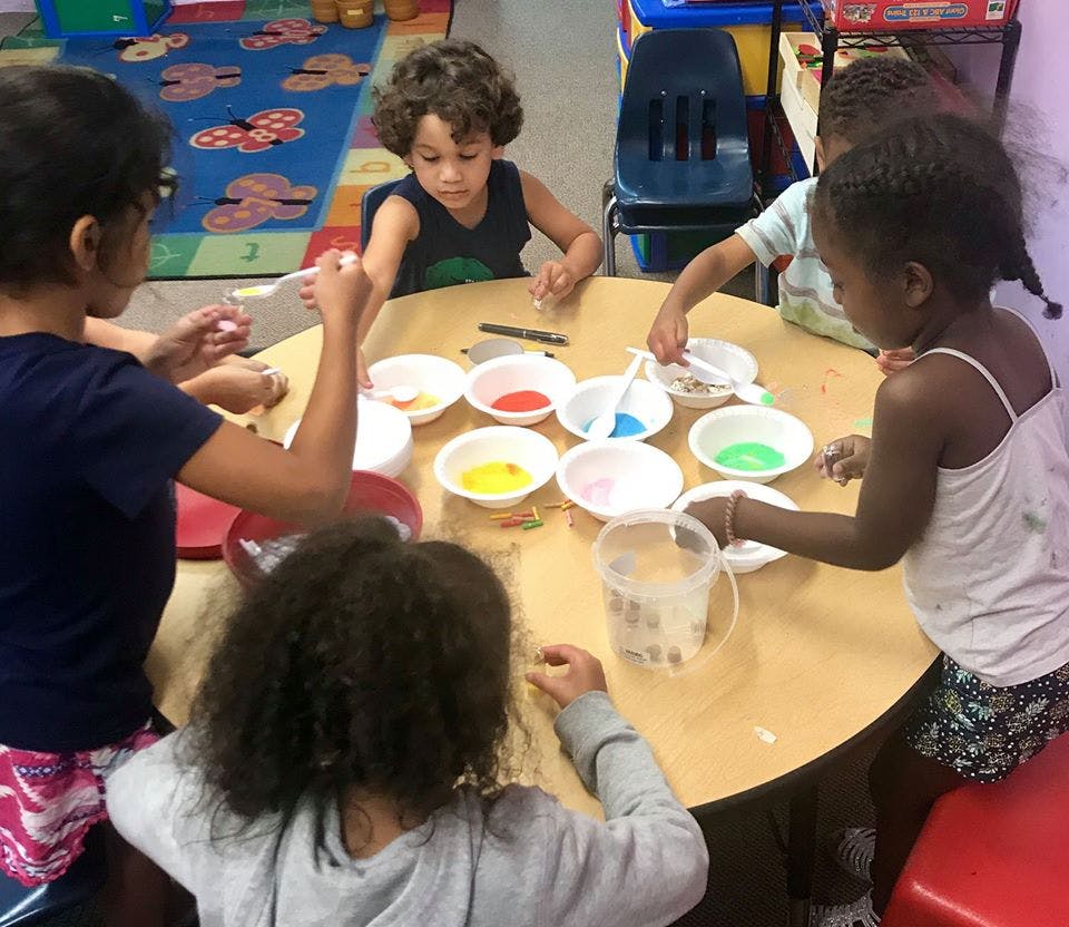 Children at a table with bowls of colorful materials