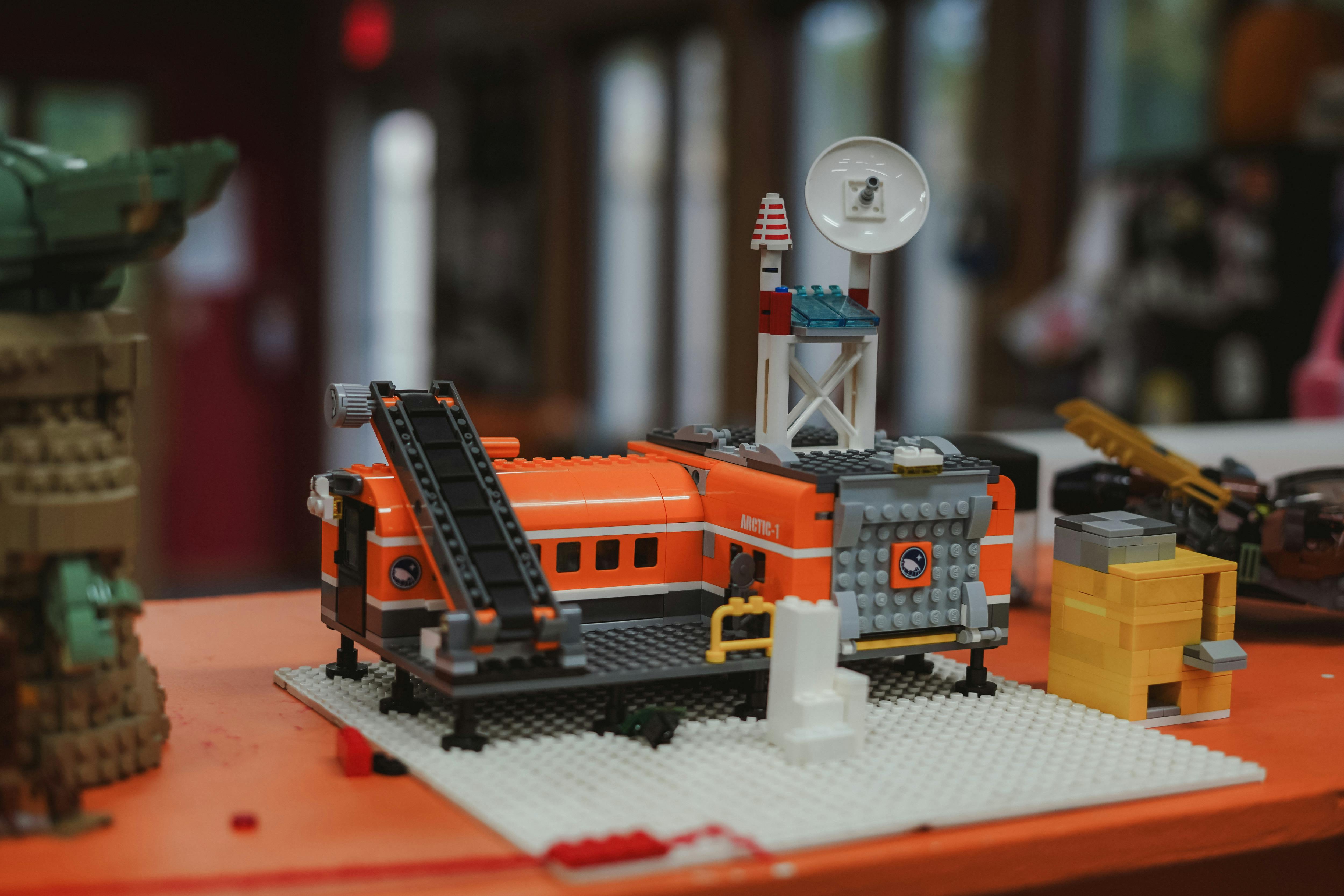 An orange and gray Lego building with a ladder and a satellite dish