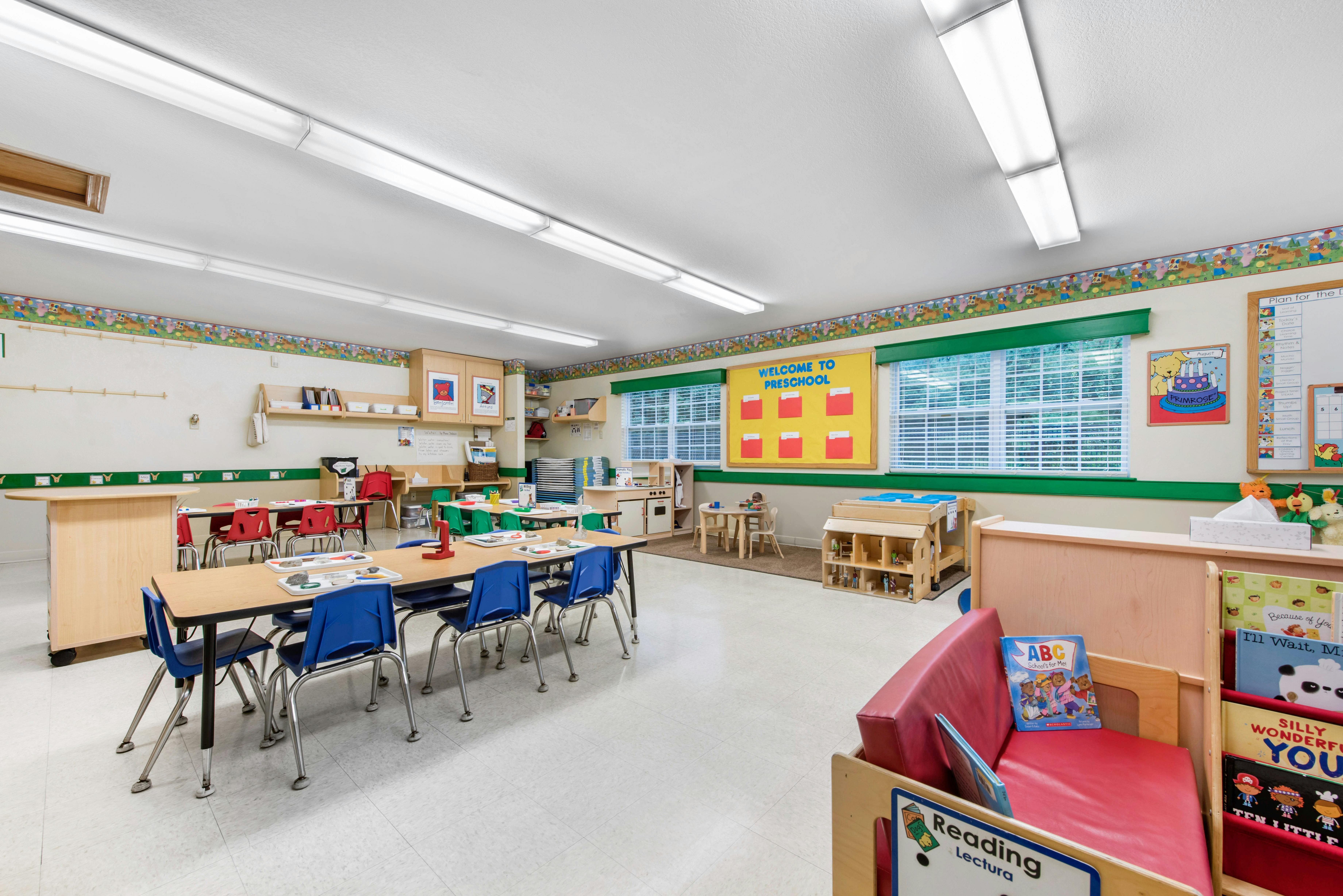 Preschool classroom with tables, chairs, and play areas with educational materials