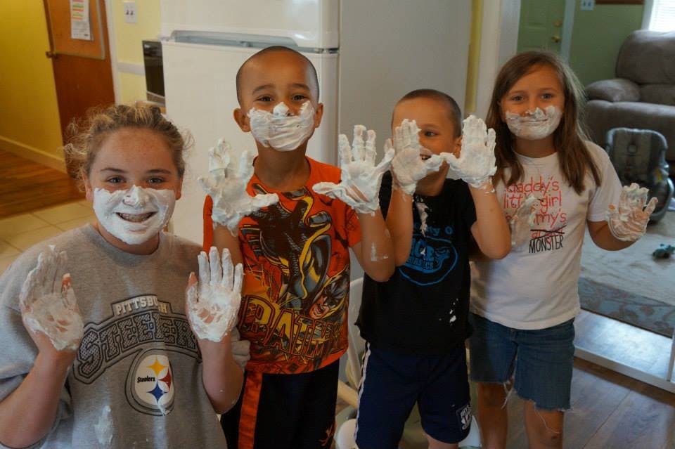Four children with shaving cream on their faces and hands