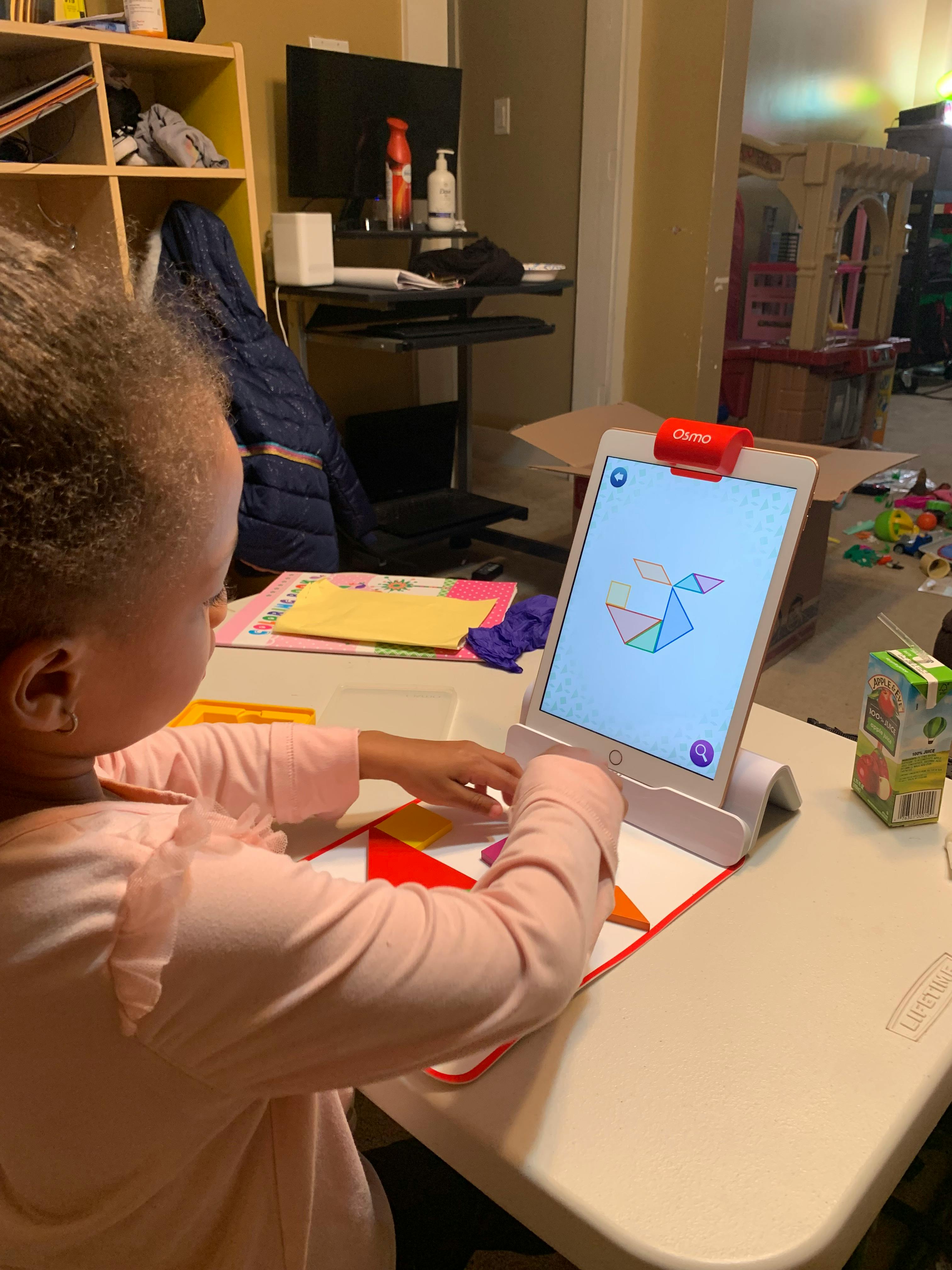 Child playing with a tablet and colorful shapes on a table