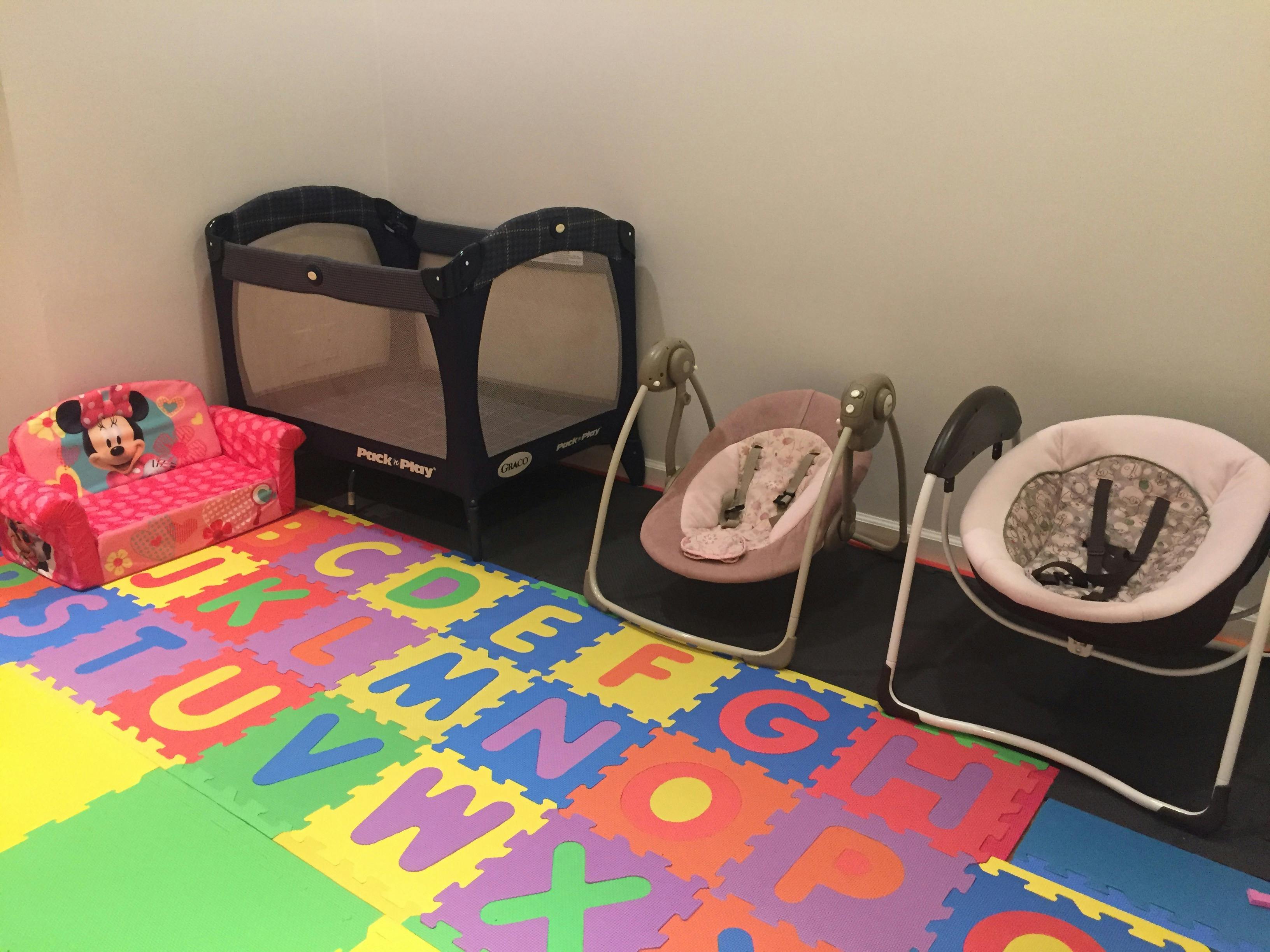 Playpen, baby swings, and child's chair on an alphabet mat