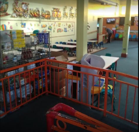 Indoor play area with tables, chairs, and a person in the background