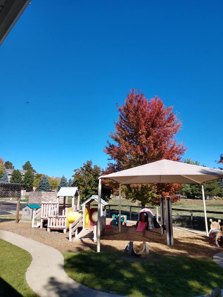 Playground with slides and climbing structures under a shade canopy