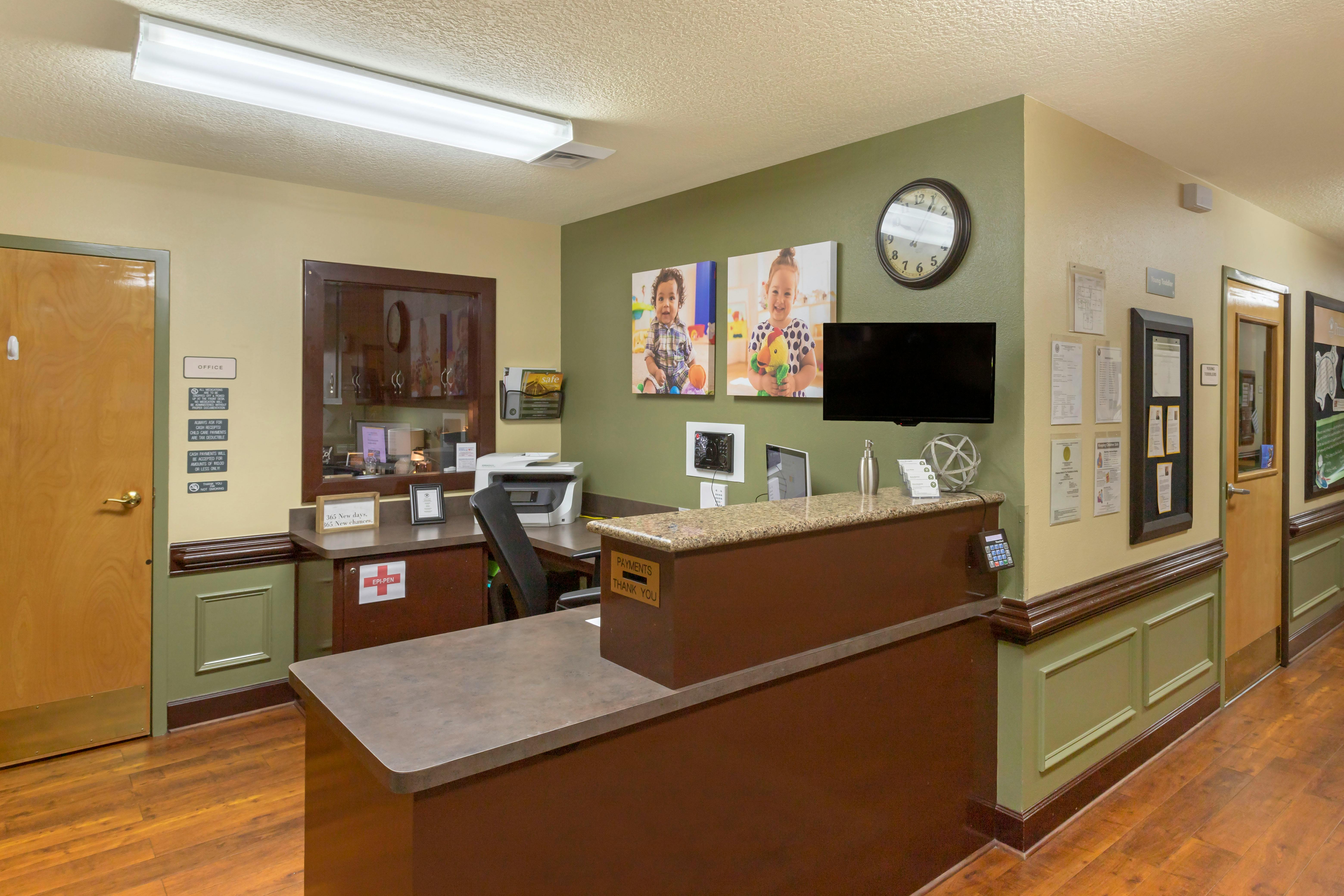 An empty reception desk area with two photos of children on the wall