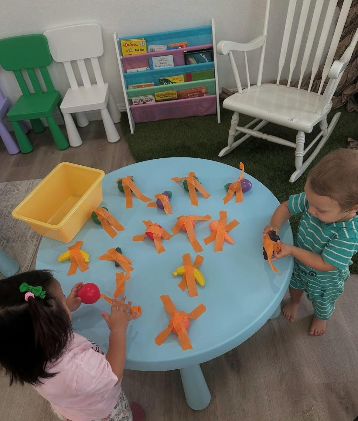 Two children playing with craft items on a blue table