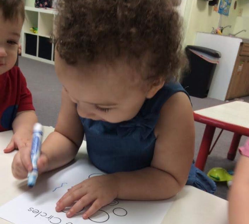 Child drawing circles on paper with a crayon