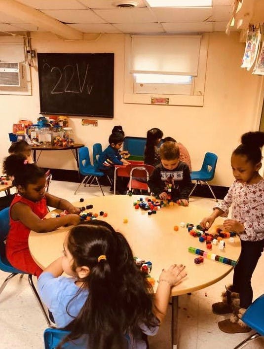 Children playing with building blocks at a round table in a classroom