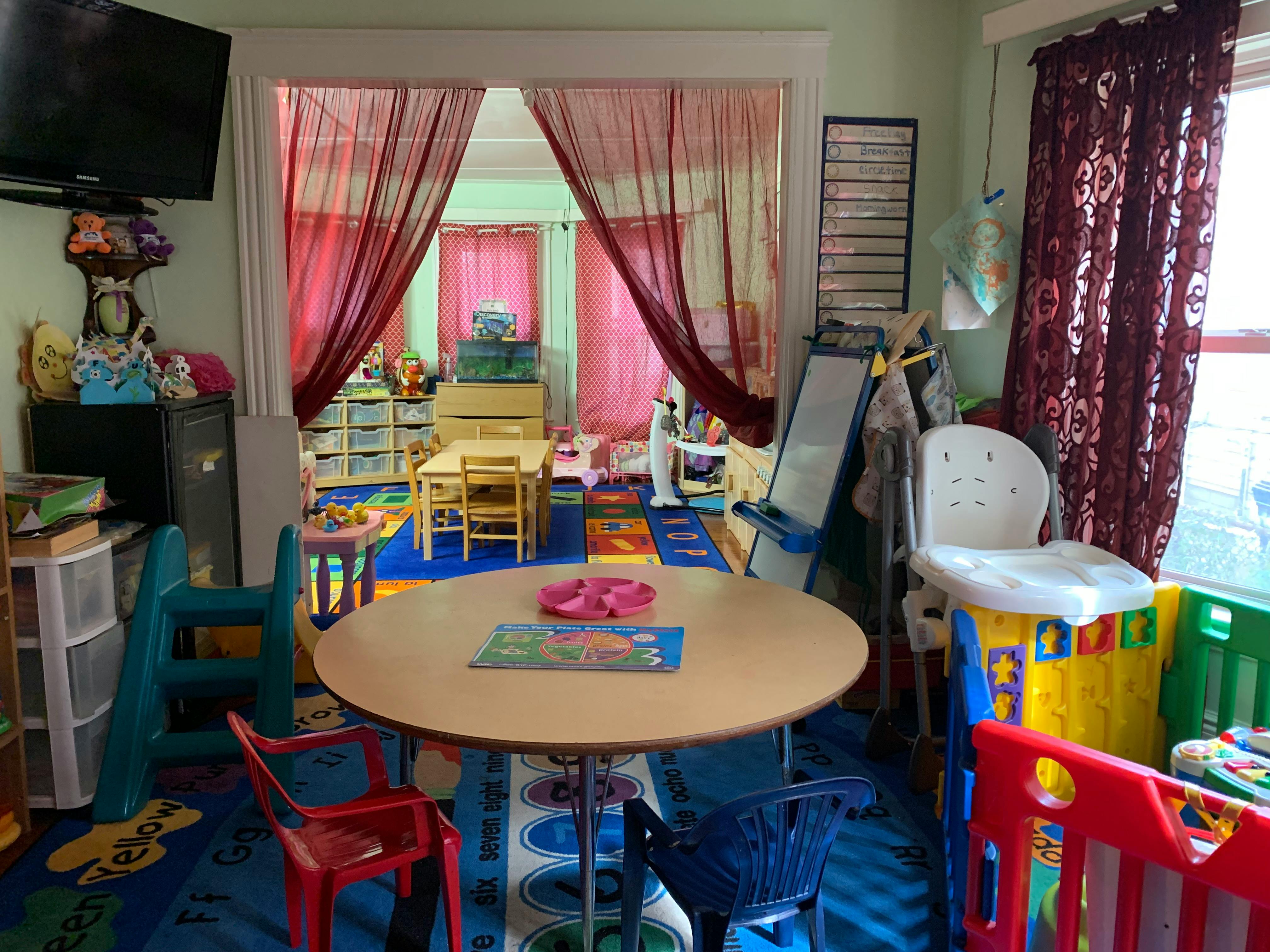 Children's room with small tables and chairs, a play slide, and alphabet rug