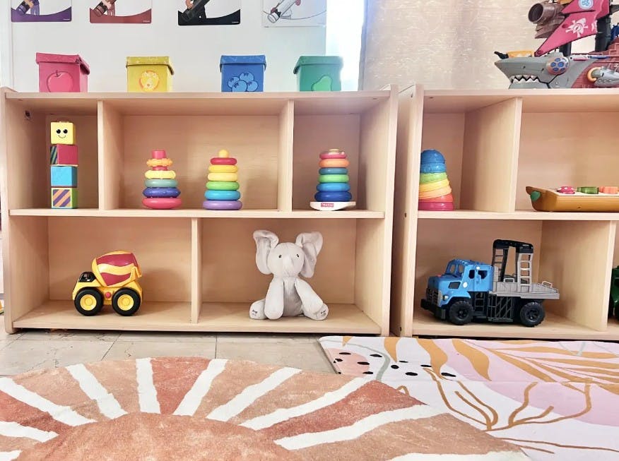 Shelves with toys including stacking rings, blocks, a truck, and a stuffed animal