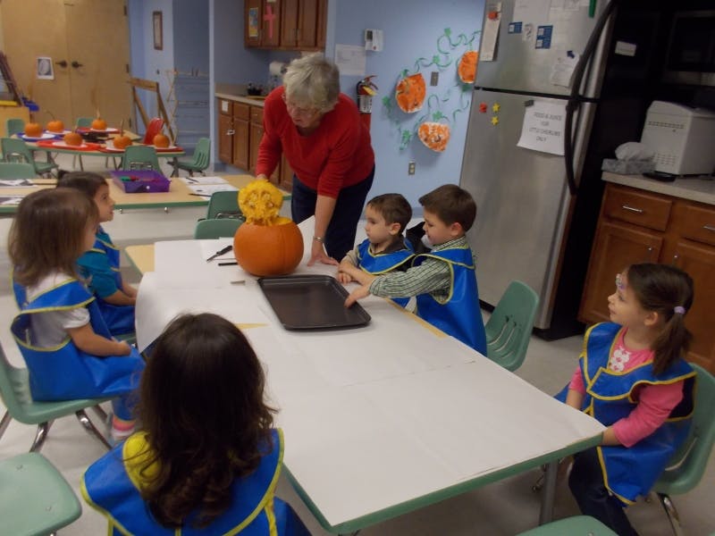 Adult and children around a table with a pumpkin