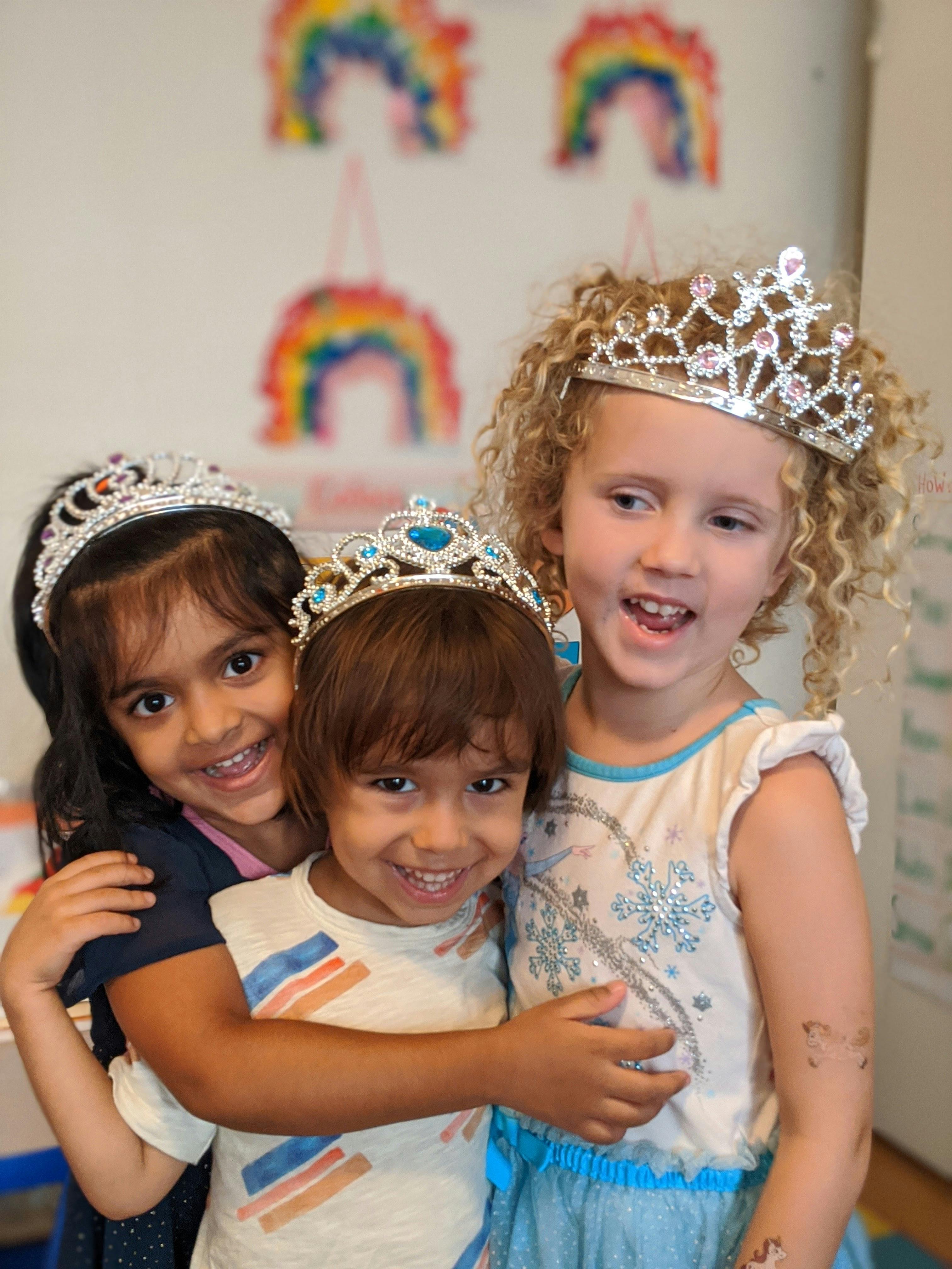 Three children wearing crowns, two embracing