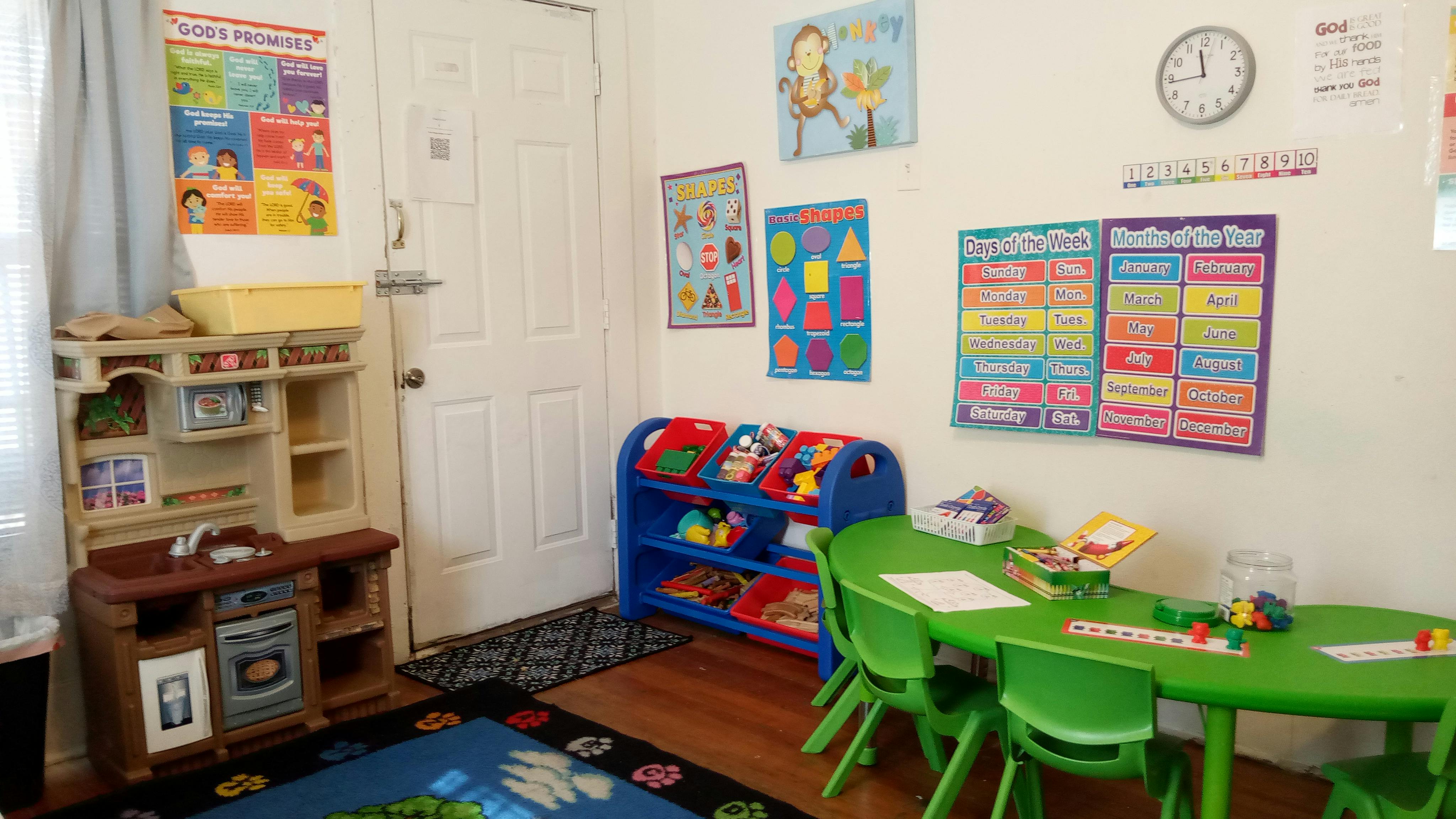 Playroom with a toy kitchen, green table and chairs, and colorful posters