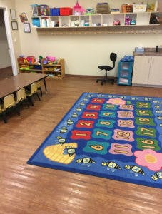 Classroom with a colorful number rug and small tables