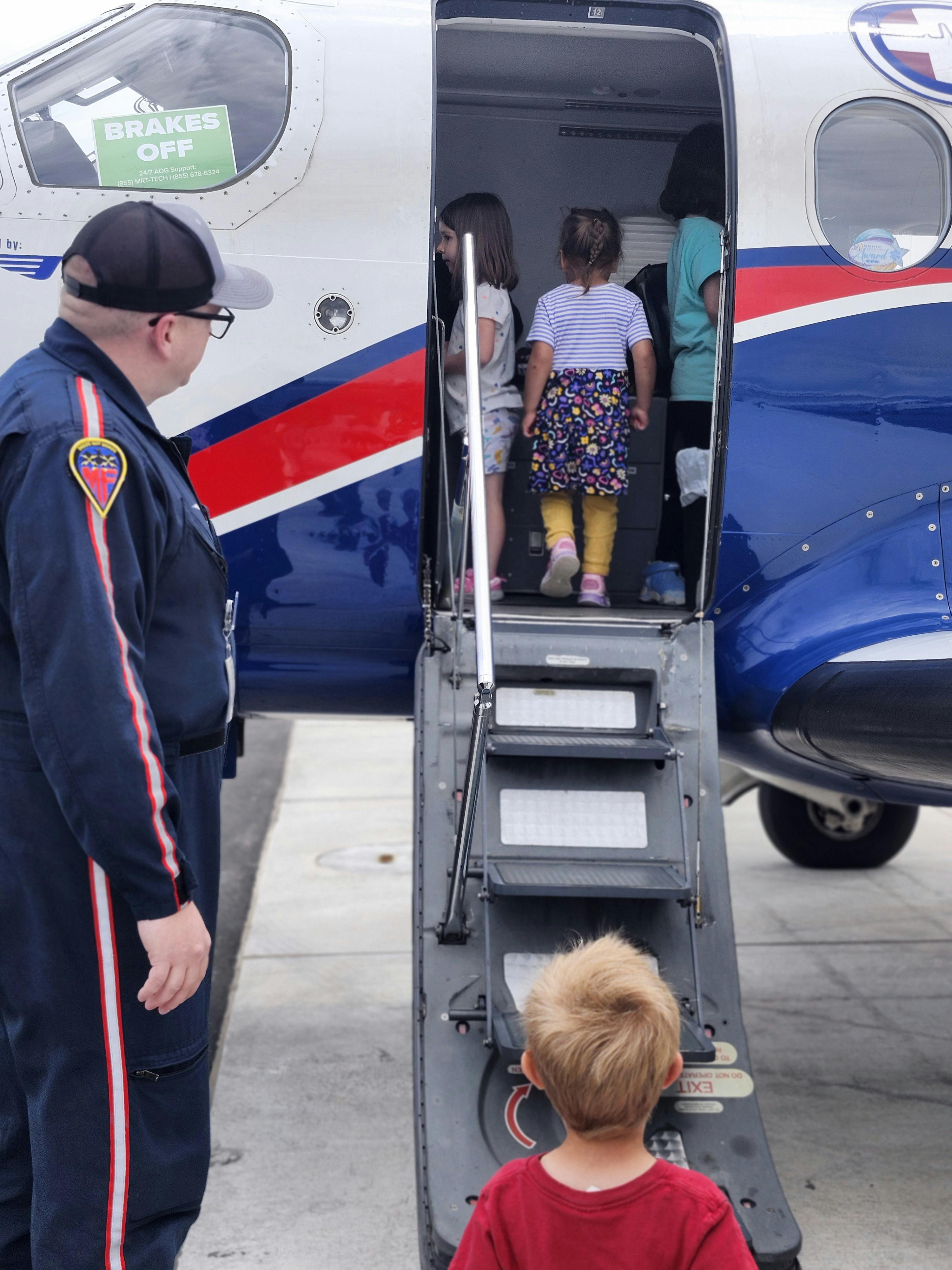 Children entering an airplane with an adult standing by