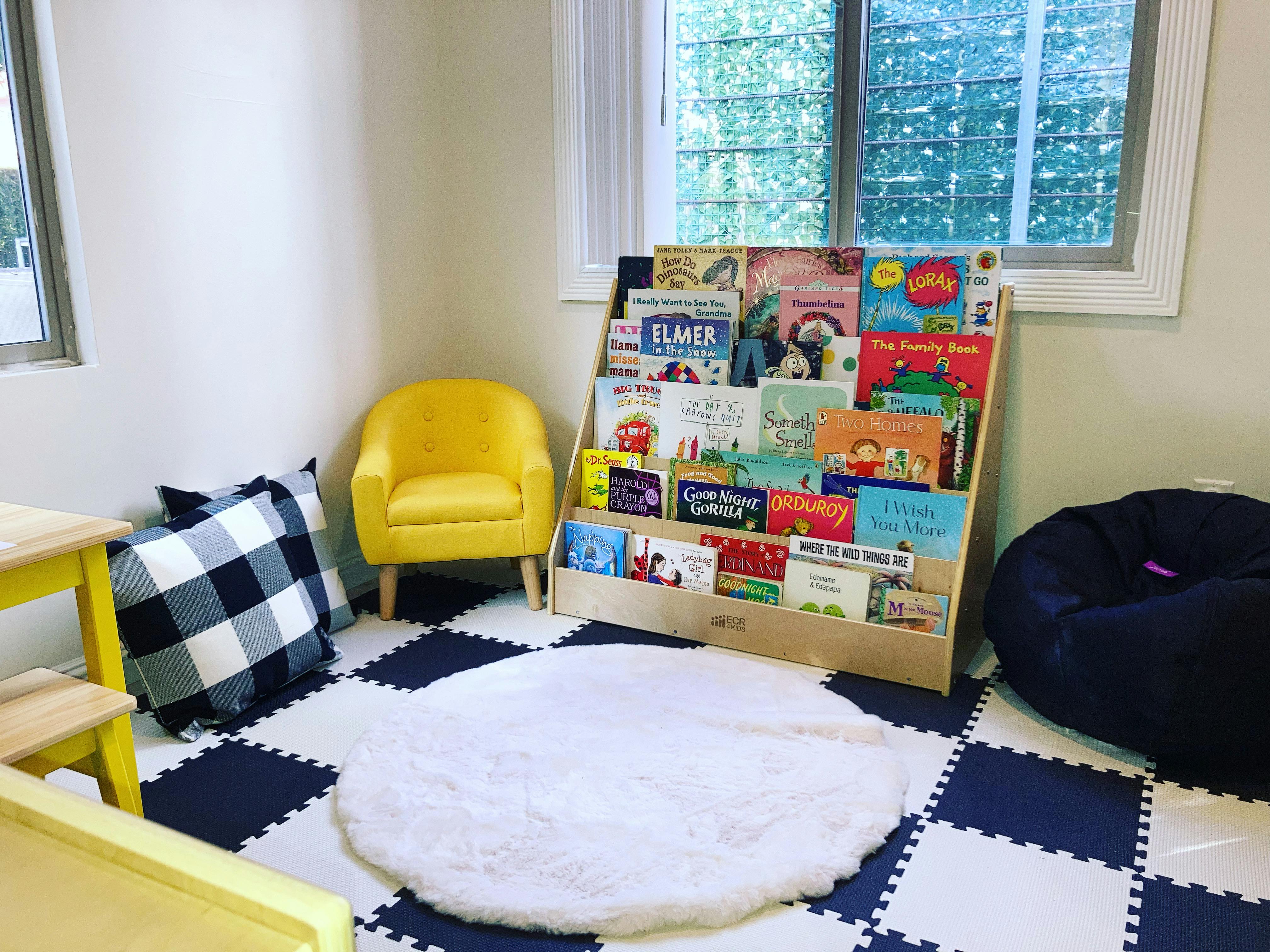 Children's reading nook with a bookshelf, yellow chair, and beanbag