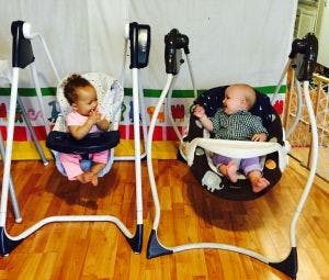Two babies sitting in baby swings
