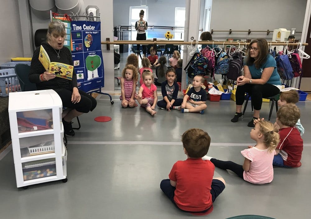 Adults reading to and talking with children sitting on the floor