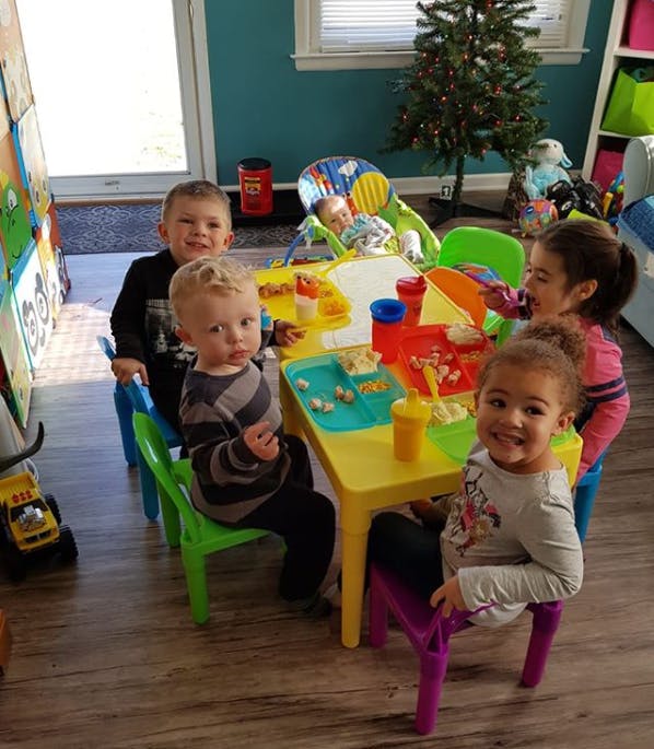 Children sitting at a small table with food and drinks