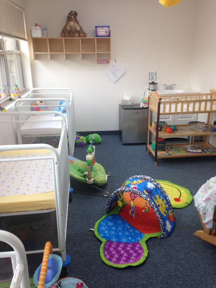 Nursery room with multiple cribs, changing table, and play mats