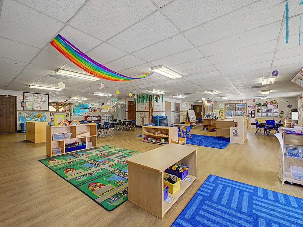 Classroom with colorful decorations, play rugs, and small tables and chairs