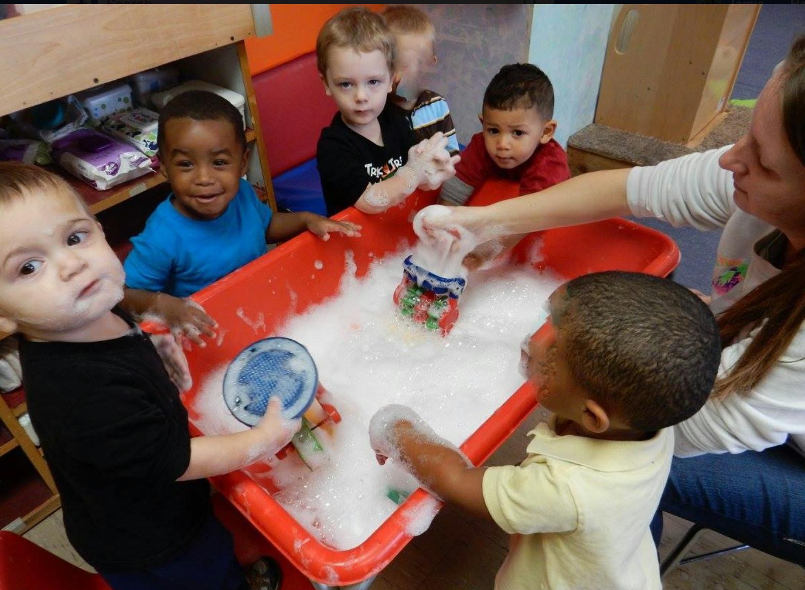 Adult and children playing with bubbles in a red bin