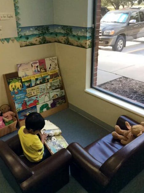 Child sitting in a chair reading a book in a classroom