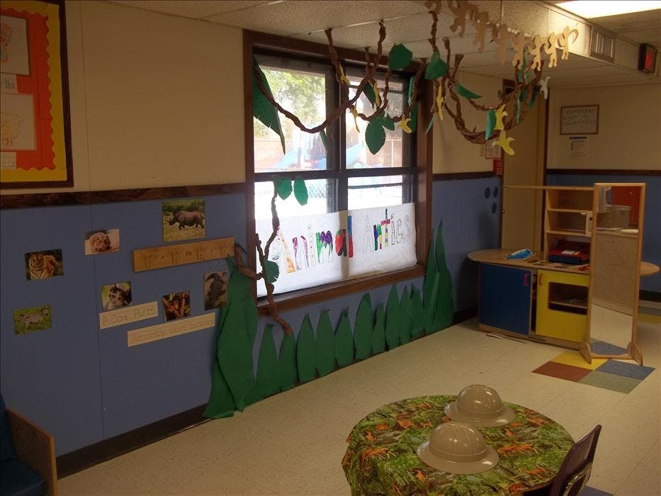 Classroom decorated with an animal theme, including vines, grass cutouts, and explorer hats