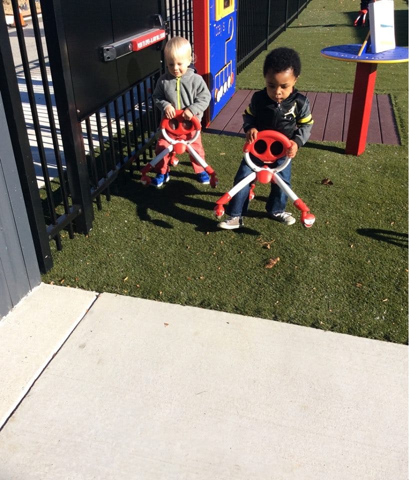 Two children standing on grass holding red and white toys