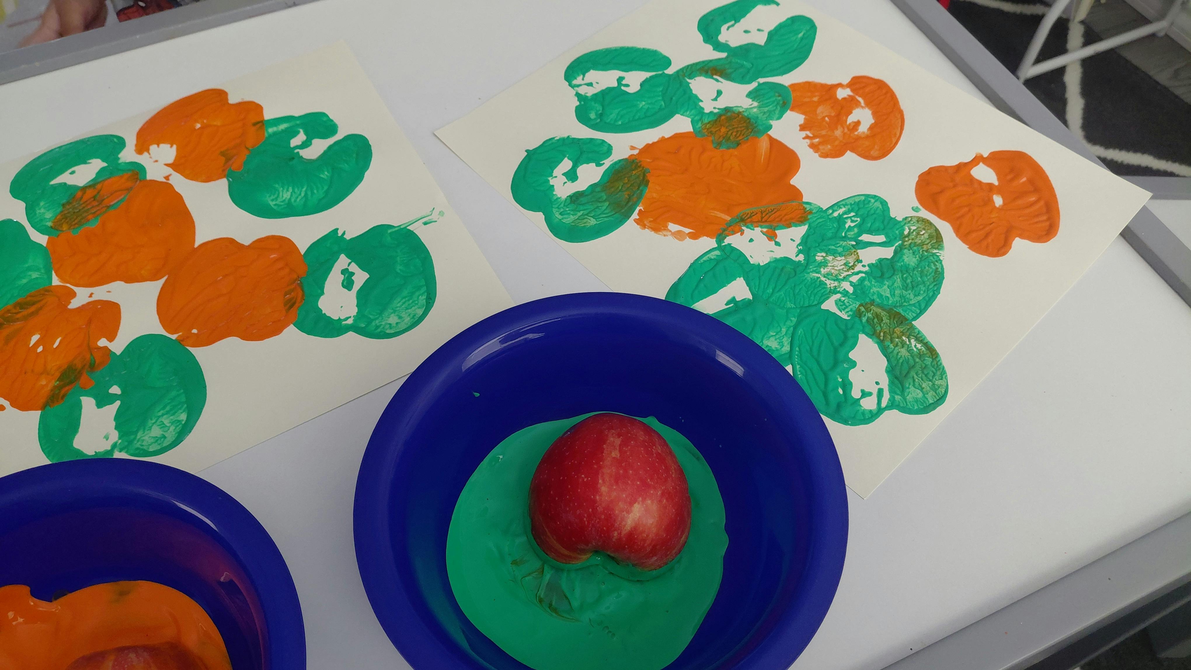 Apple printing activity with paper and bowls of paint