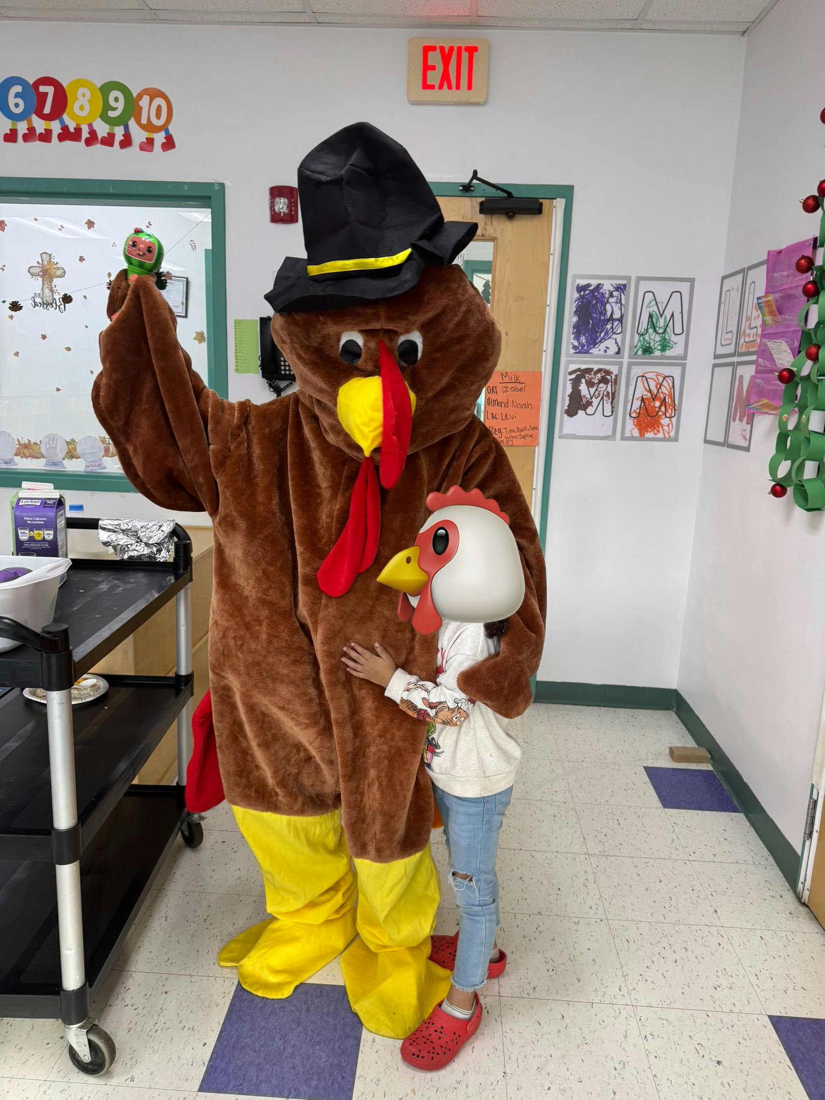 Child in chicken head mask hugging a person in a turkey costume with a pilgrim hat