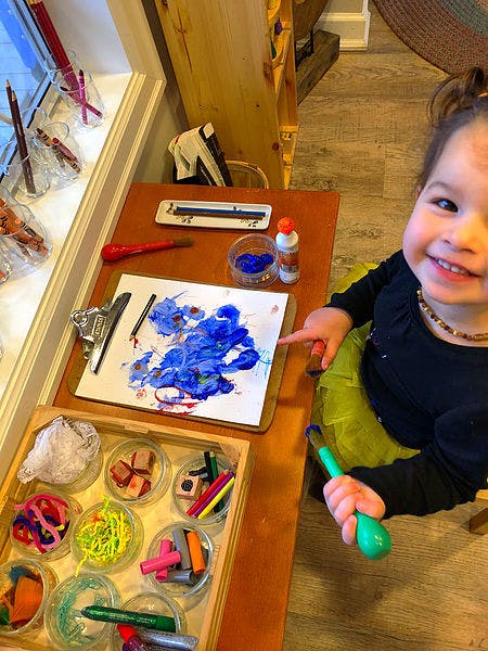 Child painting with blue paint on paper