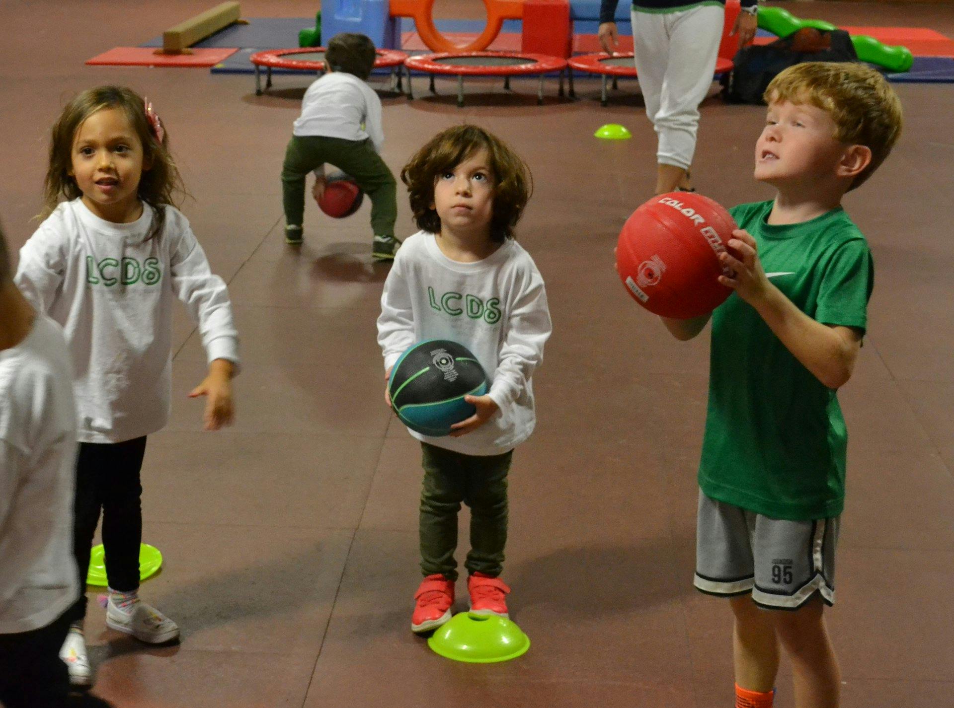 Three children playing with balls in an indoor gym