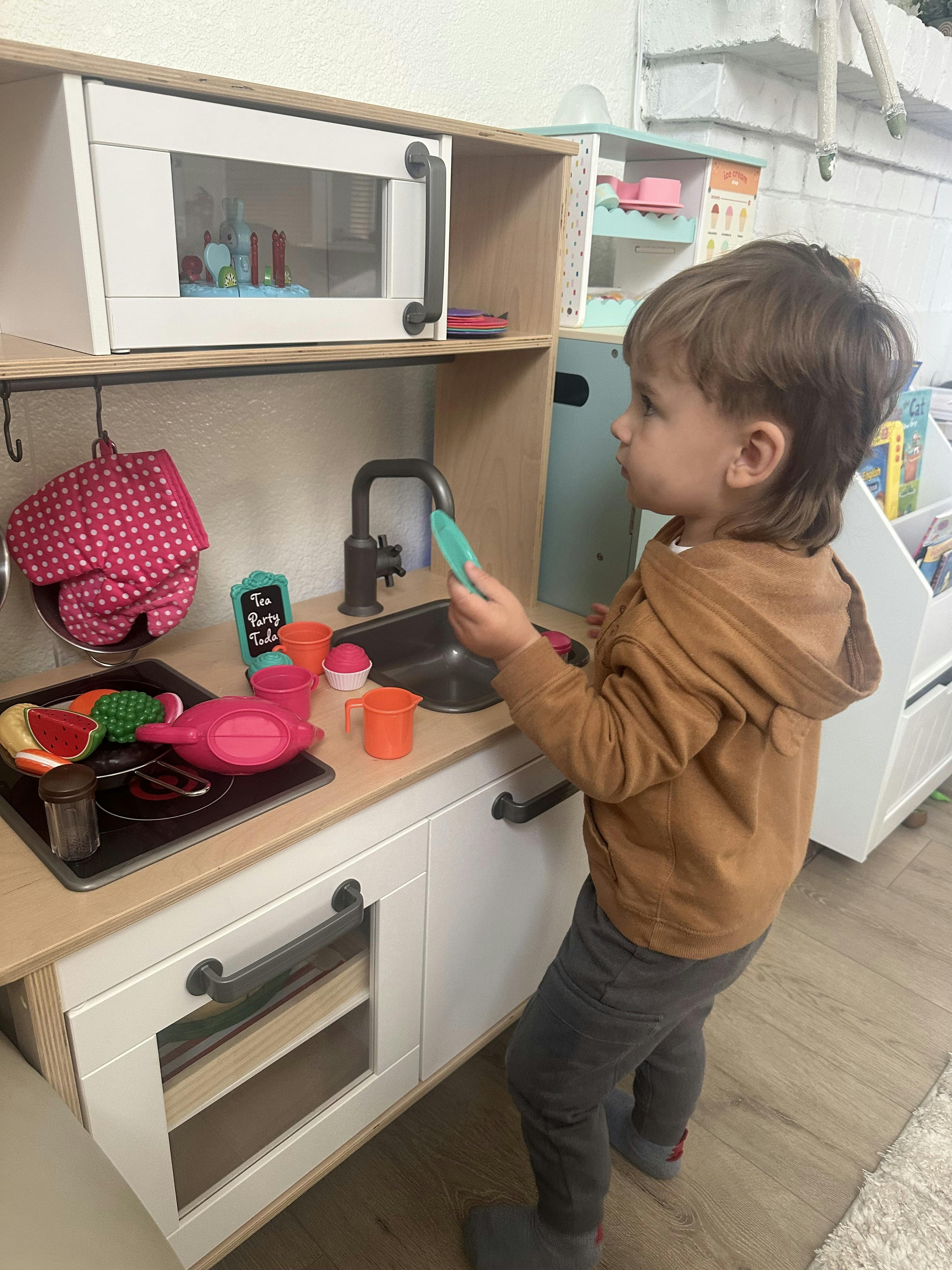 Child playing with a toy kitchen set