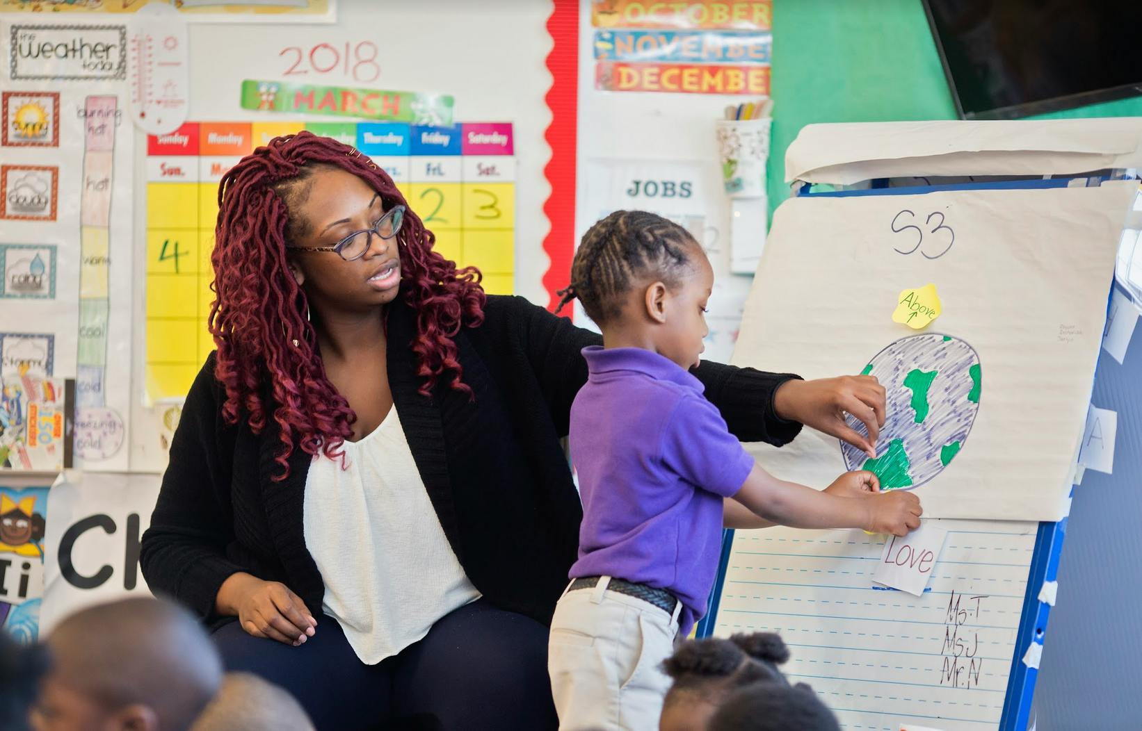 Person and child interacting with a drawing on an easel