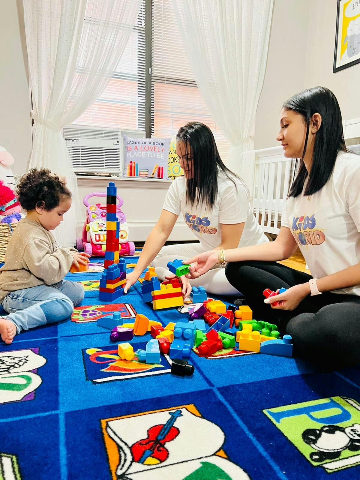 Two people and a child playing with colorful building blocks on a blue rug