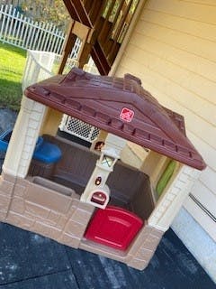 Child's playhouse with a brown roof and red door