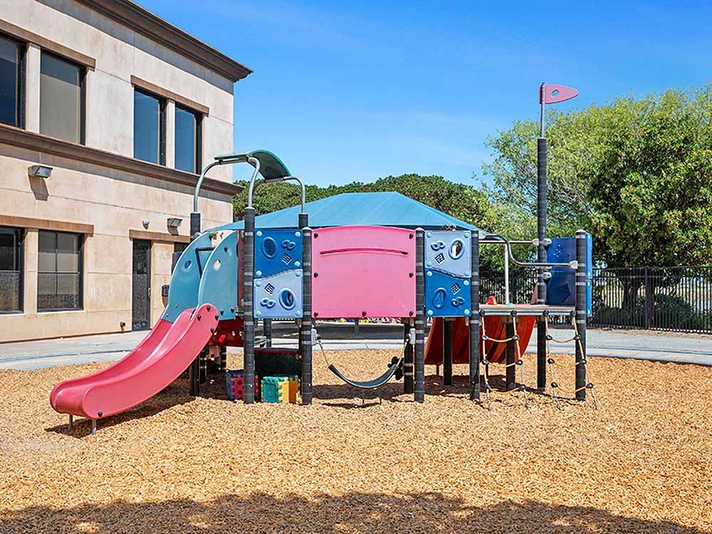 Colorful playground structure with slides on wood chip ground