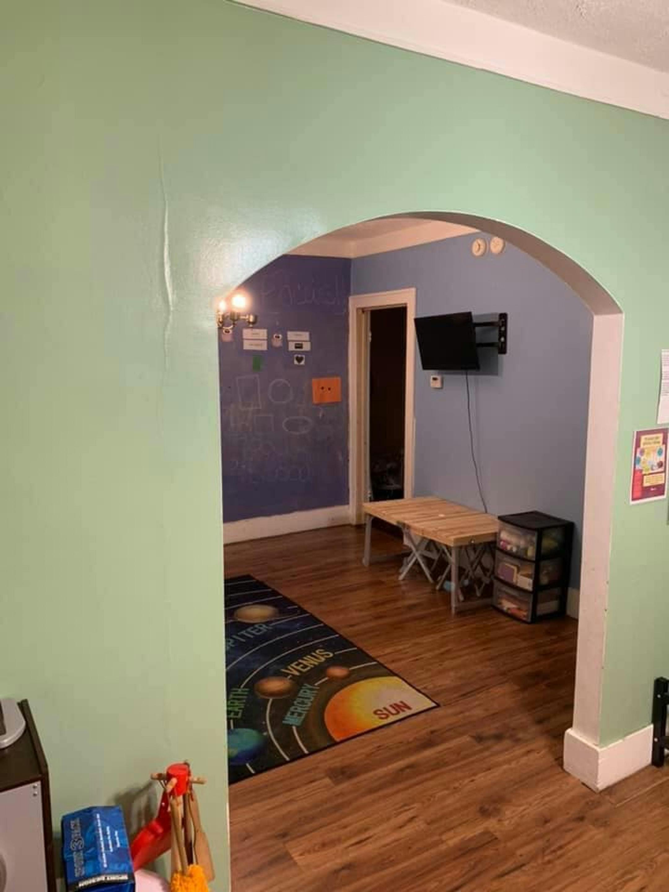 Archway leading into a room with a solar system rug and wall-mounted TV