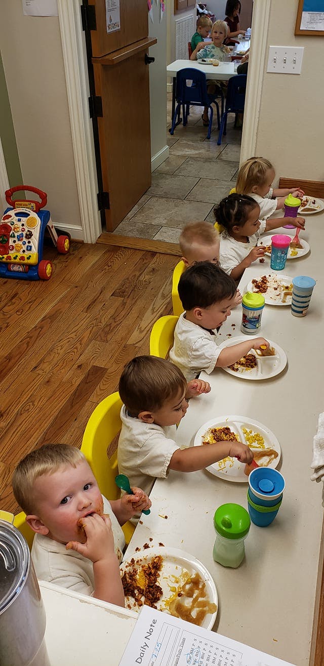 Children eating at a table in a classroom